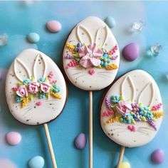 three decorated lollipops sitting on top of each other with candy in the background