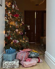 a christmas tree with presents under it in front of a door way that leads to a living room