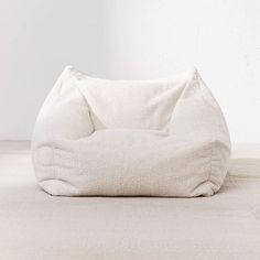 a white bean bag chair sitting on top of a wooden floor next to a wall