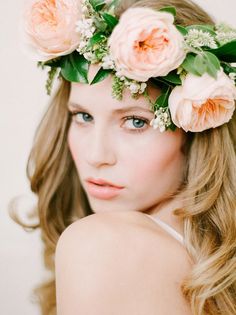 a woman with flowers in her hair is wearing a flower headpiece and looking at the camera