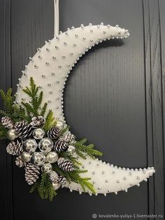 a christmas wreath made to look like the moon with pine cones and balls on it