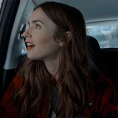 a woman sitting in the back seat of a car looking up at something on her face