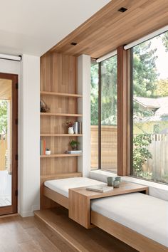 a room with wooden shelves and two white beds in it, along with open windows