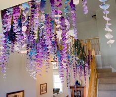 purple and blue flowers hanging from the ceiling in a house with stairs leading up to the second floor