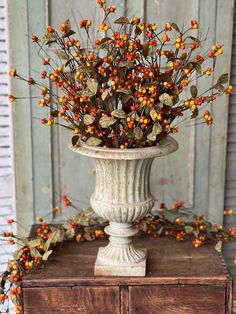 a vase filled with lots of red and yellow berries on top of a wooden table