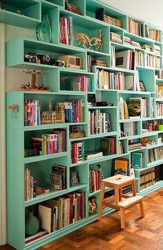 a bookshelf filled with lots of books on top of a hard wood floor