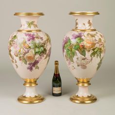 two vases with flowers on them next to a bottle