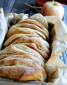 a loaf of bread sitting on top of a wooden table next to an apple and knife