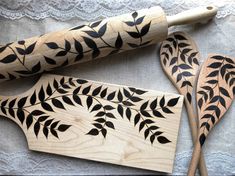 two wooden spoons, one with black leaves and the other has white lace on it