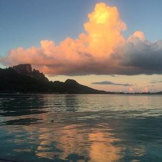 the sky is reflected in the water as clouds hover over mountains and land below