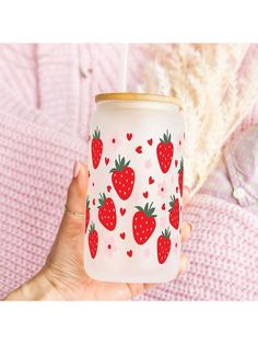 a hand holding a cup with strawberries on it and a straw in the background