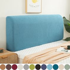 a bed with a blue headboard next to a potted plant