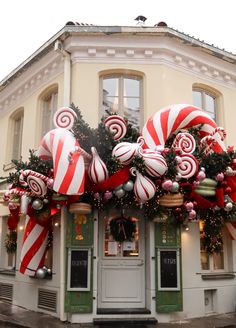 christmas decorations on the outside of a building in front of a storefront with candy canes hanging from it's windows