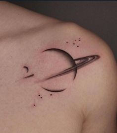 a small saturn tattoo on the back of a man's left shoulder and chest