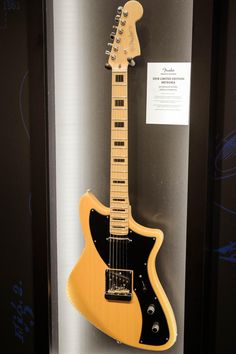 an electric guitar is on display in a glass case with black and yellow trims