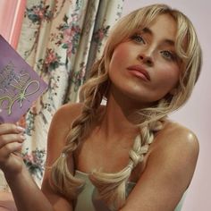 a woman holding up a purple book in her right hand and looking at the camera