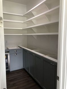 an empty kitchen with gray cabinets and white counter tops on the shelves in front of the sink