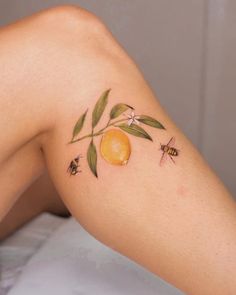 a woman's legs with tattoos on them and some fruit in the middle of her leg