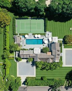 an aerial view of a tennis court and swimming pool in the middle of a lush green yard