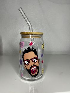 a glass jar with an image of a man sticking out his tongue and holding a straw