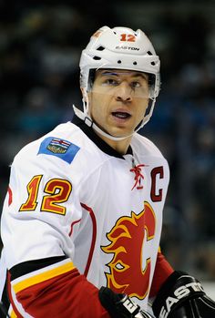 a hockey player wearing a white jersey and black gloves