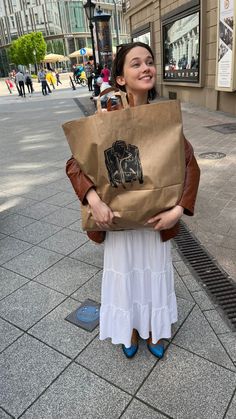 a woman is holding a brown paper bag