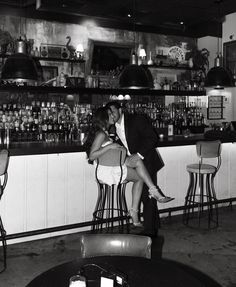 a man and woman kissing in front of a bar