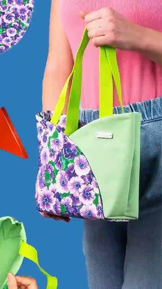 a woman holding a green and purple bag with flowers on it next to other purses