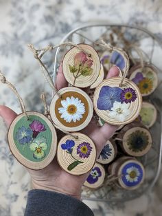 a person holding some wood slices with flowers on them