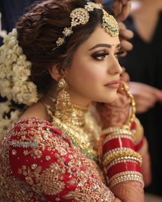 a woman in a red and gold bridal outfit is getting ready to go on her wedding