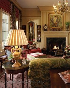 a living room filled with furniture and a fire place under a chandelier in front of a fireplace