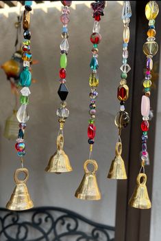 several bells hanging from the ceiling in front of a window with glass beads on them