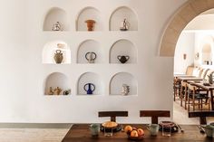 a dining room table with bowls and vases on the shelves above it, along with other plates and utensils