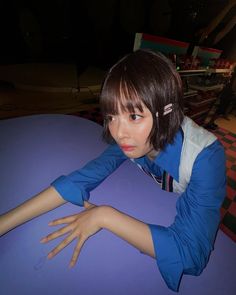 a young woman sitting at a table with her hand on top of the table and wearing headphones