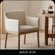 a white chair sitting on top of a rug next to a table with a cup