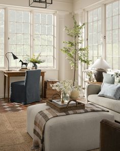 a living room filled with furniture and lots of windows covered in shades of blue, white and brown