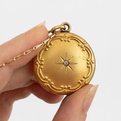 "This antique gold filled Edwardian or Victorian necklace features a photo locket pendant decorated in Art Nouveau repousse of a starburst around a paste gemstone. It hangs on n unusual and seemingly gold plated or filled chain. This item is not marked.   This locket measures about 1 1/8 inches in diameter (not including its bail) while its chain is about 24 inches long. The locket does not have locket frames or covers. It closes with a strong \"snap\"." Gold Heirloom Brass Locket Necklace, Heirloom Gold Brass Locket Necklace, Heirloom Gold Pendant Locket Necklace, Yellow Gold Brass Jewelry With Star Charm, Yellow Gold Amulet Jewelry With Vintage Charm, Keepsake Yellow Gold Brass Locket Necklace, Heirloom Yellow Gold Medallion Locket Necklace, Keepsake Yellow Gold Locket Necklace In Brass, Antique Gold Amulet Locket Jewelry