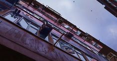 an apartment building with lots of windows and balconies on the top floor, against a cloudy blue sky