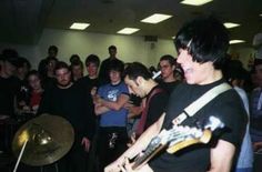 a group of young men standing next to each other in front of a crowd holding musical instruments