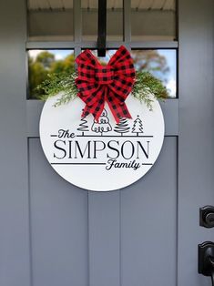 a red and black bow hangs on the front door of a house that says simpson family