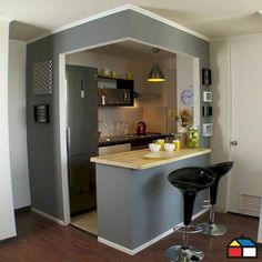 a kitchen with an island and bar stools in the middle, next to a refrigerator