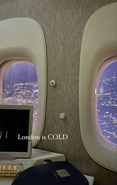 an airplane window with the view of city lights from inside and below it, as well as a laptop computer