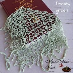 a crocheted doily next to a book on a white tablecloth with text that reads, may catholic church