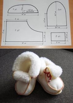 a pair of baby shoes sitting on top of a table next to a paper pattern