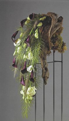 an arrangement of flowers and greenery on a metal stand