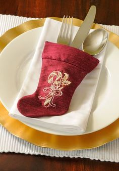 a red christmas stocking sitting on top of a white plate next to a fork and knife