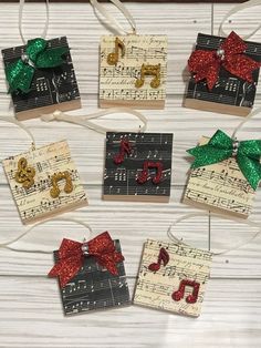 christmas ornaments made out of sheet music and red, green, and gold bows hanging from strings