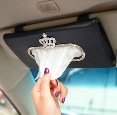 a woman's hand holding a napkin with a tiara on it in the back seat of a car