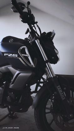 a black motorcycle parked in a garage next to a wall