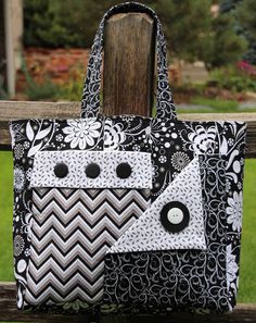 a black and white handbag sitting on top of a wooden fence